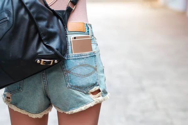 Giovane e carina ragazza ha il cellulare in tasca jeans — Foto Stock