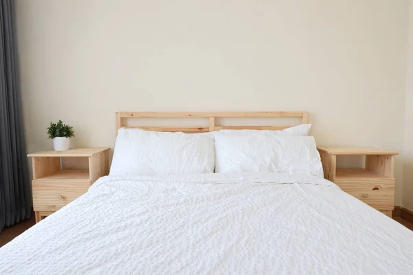 Vorderseite des neuen modernen weißen Holzbettes im weißen Schlafzimmer mit weichem und klarem Licht, oben Kopierraum — Stockfoto