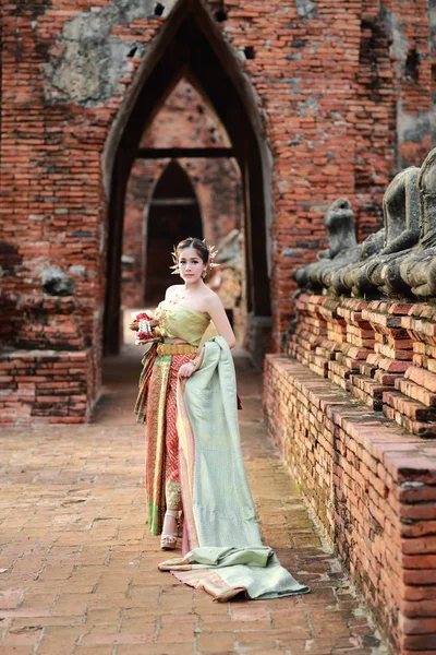 Moda asiático chica en tailandés tradicional traje en antiguo templo con volante flor en la mano — Foto de Stock