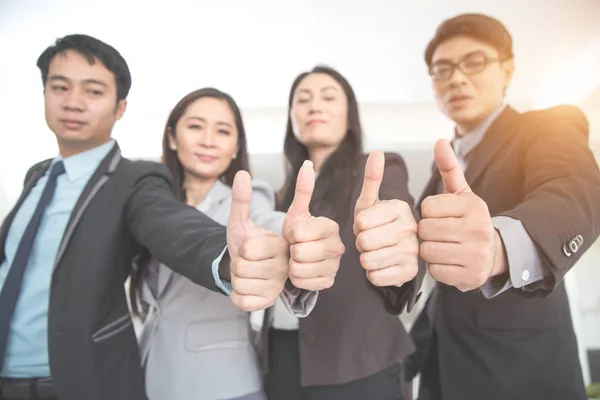 Affärsfolk ger tummen upp efter avslutade projekt under mötet med som bakgrund (begreppet teamwork och partnerskap) — Stockfoto