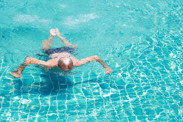 Feliz anciano caucásico nadar en la piscina durante las vacaciones de jubilación con la relajación y sonriendo — Foto de Stock