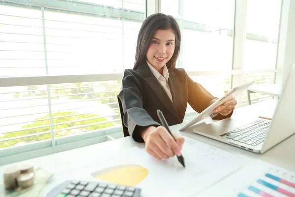 Geschäftsfrau, die Tablet und Laptop benutzt, während sie an einem zusammenfassenden Bericht mit Grafik arbeitet — Stockfoto
