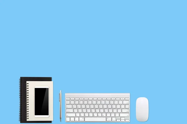 Mesa de espaço de trabalho com computador portátil, material de escritório, xícara de café, telefone celular e xícara de café no fundo pastel azul — Fotografia de Stock