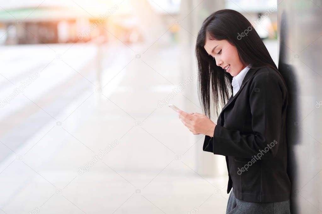 asian businesswoman standing in downtown and using smartphone