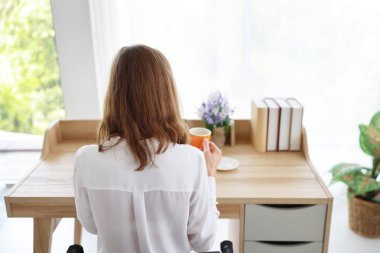 yatak odasında ahşap masada dizüstü bilgisayar ve cep telefonu ile sabah kahve veya çay bir fincan içme güzel kız arka görünümü