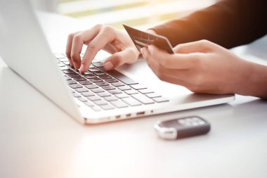 kadın eller aylık ödeme için dizüstü bilgisayar, kredi kartı ve araba anahtarı kullanın