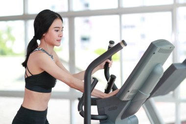 spor salonunda egzersiz makinesi kullanarak genç sağlıklı ve sportif kadın portresi 