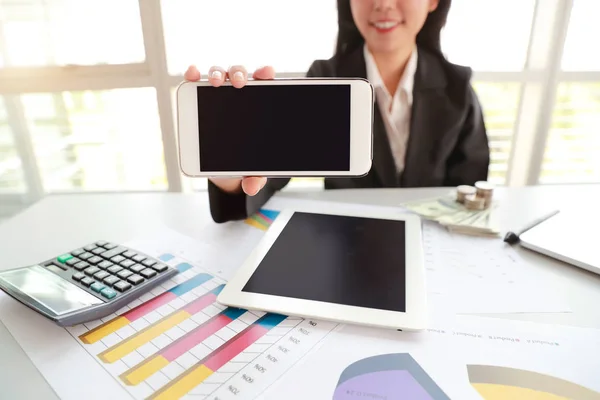 Geschäftsfrau zeigt leeres Bildschirm-Handy mit Tablet auf Tisch — Stockfoto