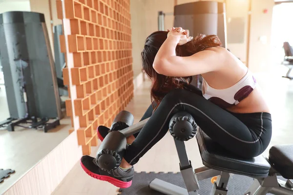 Retrato de jovem mulher saudável e desportiva usando máquina de exercício no ginásio (esta imagem para fitness e conceito de treino ) — Fotografia de Stock