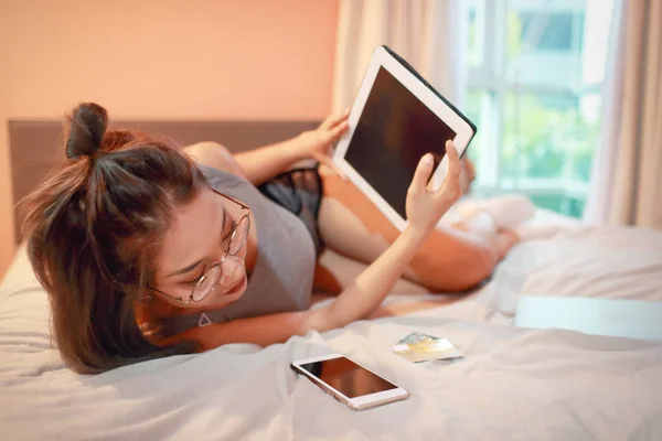 Hermosa y sexy mujer usando tableta y teléfono celular antes de ir a dormir —  Fotos de Stock