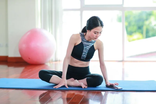 sporty girl practicing yoga and stretching from cell phone in gym