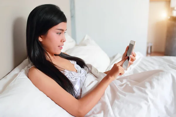 Mujer joven y sexy usando el teléfono celular en la cama —  Fotos de Stock