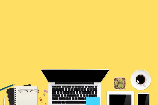 Flat lay workspace table with laptop computer, office supplies, coffee cup, tablet and cell phone on yellow pastel background — Stock Photo, Image