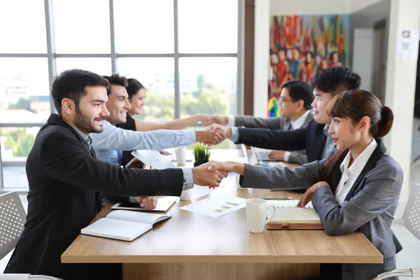 Multietniskt affärsfolk diskuterar företag om nya projekt i mötesrum då de skakar hand innebörden av sitt jobb är framgång med leende och glada ansikten — Stockfoto