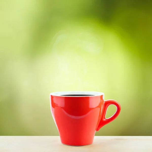 Una tazza di caffè rosso con vapore sulla scrivania in legno con spazio copia superiore e sfondo verde natura (colazione rinfresco ) — Foto Stock