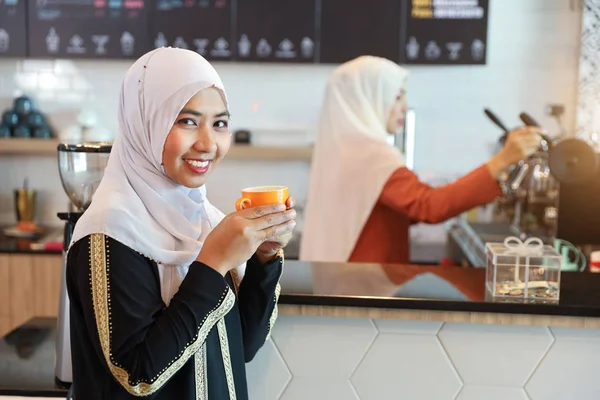 Cliente muçulmano beber café no balcão com jovem barista muçulmano menina desfocado fundo — Fotografia de Stock