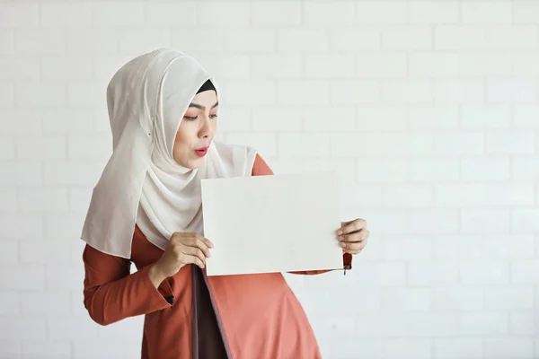 Jovem mulher de negócios muçulmana mostrando papel branco em branco e apontando-o (você pode colocar carta sobre ele ) — Fotografia de Stock