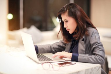 dizüstü bilgisayar ve cep telefonu kullanarak gözlük ile çalışan ve büyüleyici kadın (ev konsepti nden iş)