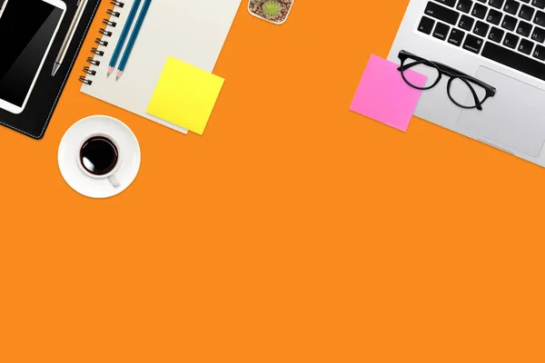 Eenvoudige werkruimte technologie oranje tafel met laptop computer, koffie kopje notebook en kopieer ruimte — Stockfoto