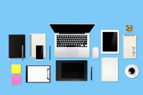 Tabulka pracovního prostoru s přenosným počítačem, kancelářskou potřebami, šálkem kávy, mobilním telefonem a šálkem kávy na modrém pastelovém pozadí — Stock fotografie