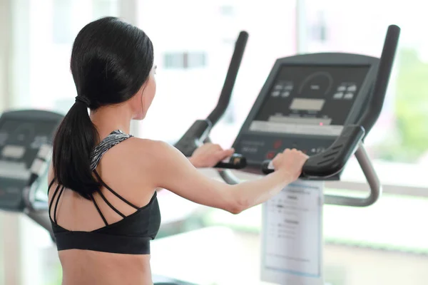 Portrét mladé zdravé a sportovní ženy používající cvičný stroj v tělocvičně — Stock fotografie