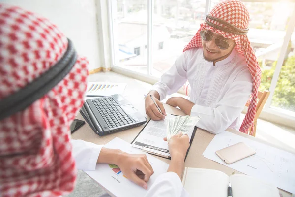 Arab Saudi affärsman ta emot pengar efter undertecknandet kontrakt med som affärsbakgrund (begreppet teamwork och partnerskap) — Stockfoto