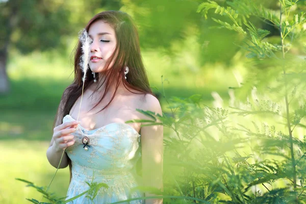 Мила і красива дівчина стоїть на природі на відкритому повітрі і тримає на руці трав'яні квіти — стокове фото