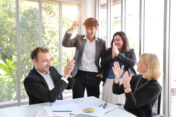 Multietniska affärsmänniskor diskuterar företagets vinst eller projektresultat i mötesrum då de klappar sina händer mening med sitt jobb är framgång med leende och glada ansikten — Stockfoto