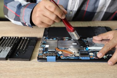 teknisyen adam dizüstü bilgisayar temizlemek için bir toz fırçası kullanarak