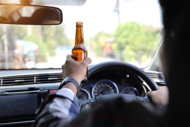 adam araba sürme ve yolda iken başka bir elinde alkol şişesi tutarak 