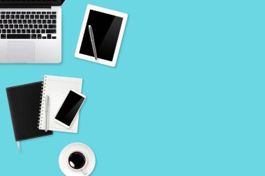 Teknoloji çalışma masasında dizüstü bilgisayar, ofis malzemeleri, kahve fincanı, tablet ve yeşil pastel arka planda cep telefonu.