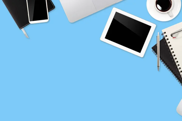 Tabulka pracovního prostoru s přenosným počítačem, kancelářskou potřebami, šálkem kávy, mobilním telefonem a šálkem kávy na modrém pastelovém pozadí — Stock fotografie