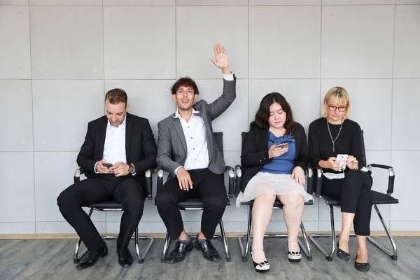 Personas que se alinean para la entrevista de RRHH jugando teléfono inteligente y sentado durante la espera y asiático hombre de negocios levantando la mano a alguien — Foto de Stock