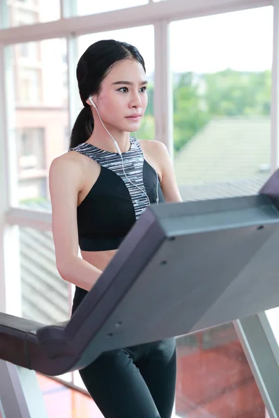 Молода здорова спортивна дівчина ходить і слухає музику на тренажерному автоматі в тренажерному залі (концепція тренування ) — стокове фото