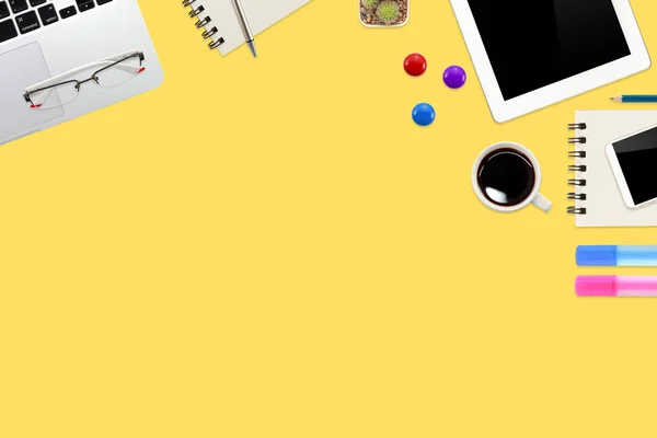 Plateau de travail plat avec ordinateur portable, fournitures de bureau, tasse à café, tablette et téléphone portable sur fond jaune pastel — Photo