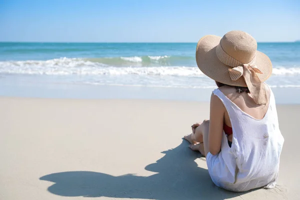 Vista posterior retrato de sexy chica joven asiática en bikini y sombrero, mirando hacia la playa tropical mientras está sentado en la playa de arena en la naturaleza con cielo azul . — Foto de Stock