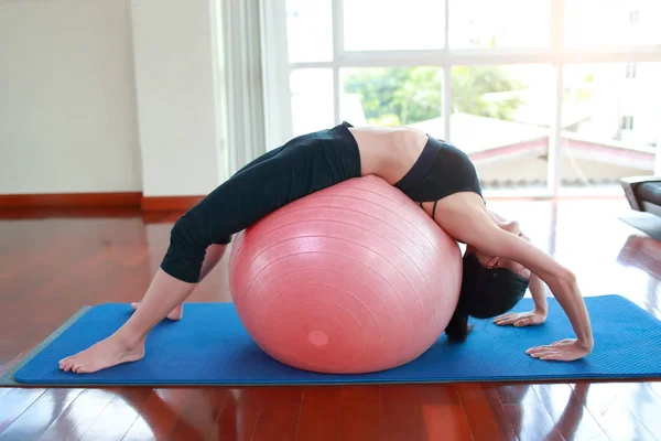 Jonge gezonde en sportieve vrouw doen yoga indoor met roze bal — Stockfoto