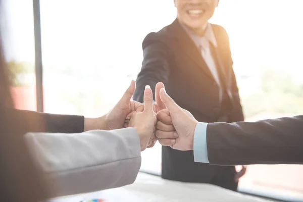 Affärsfolk ger tummen upp efter avslutade projekt under mötet med som bakgrund (begreppet teamwork och partnerskap) — Stockfoto