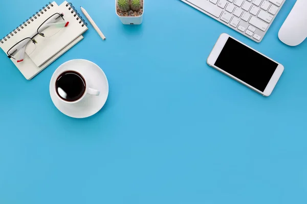 Vista superior escritorio de oficina de pastel azul con computadora, suministros de oficina, teléfono celular y taza de café negro — Foto de Stock