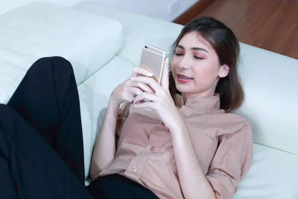 Mujer joven usando el teléfono celular en la sala de estar —  Fotos de Stock