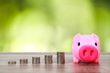 doğa arka plan ile ahşap masa üzerinde yığın sikke ile piggy