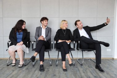 İk görüşmesi için sıraya giren kişiler beklerken kendilerini akıllı telefondan fotoğraf çekmek 