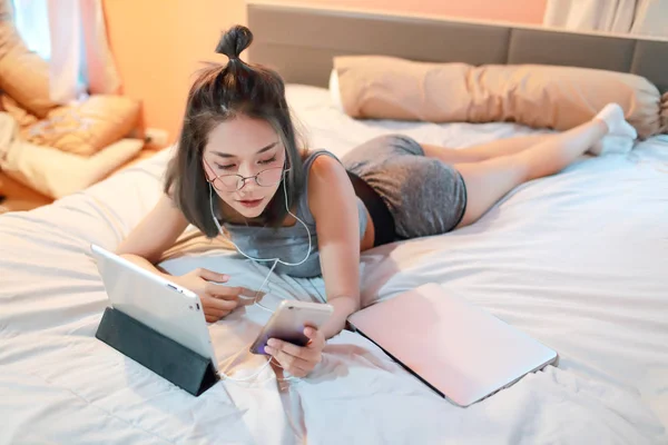 Mooie en sexy vrouw met behulp van laptop computer en luisteren naar muziek van mobiele telefoon op bed — Stockfoto