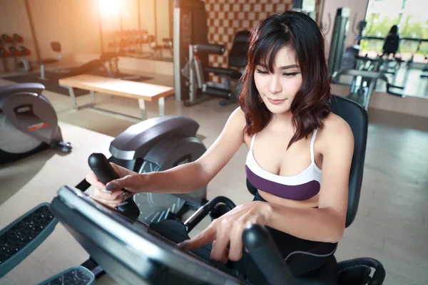 Portrét mladé zdravé a sportovní ženy pomocí cvičebního stroje v tělocvičně (tento obrázek pro fitness a cvičení koncept) — Stock fotografie