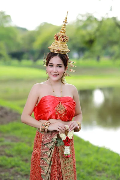 Μόδα κορίτσι της Ασίας στην ταϊλανδέζικη παραδοσιακή στολή στον αρχαίο ναό με το τιμόνι λουλούδι στο χέρι — Φωτογραφία Αρχείου