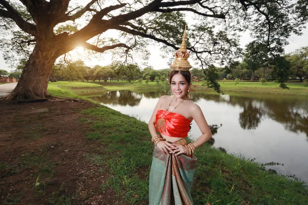 Moda asiático chica en tailandés tradicional traje en antiguo templo con volante flor en la mano y feliz cara — Foto de Stock