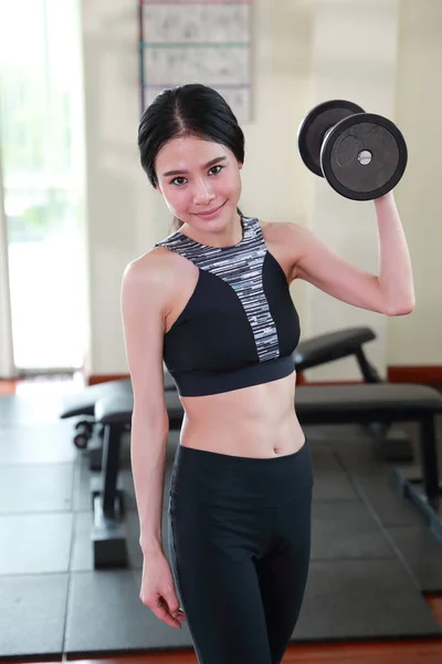Sağlık seven genç asyalı sağlıklı kadın gülümseyen yüzü ile fitness dambıl kaldırarak egzersiz yapıyor (spor salonu kavramı egzersiz) — Stok fotoğraf