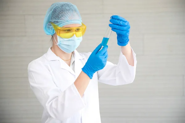 scientist woman with equipment and laboratory glassware holding chemical liquid and checking result using as science research background