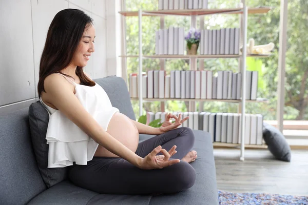 Mladá těhotná žena, která se baví medituje v místnosti s jóga — Stock fotografie