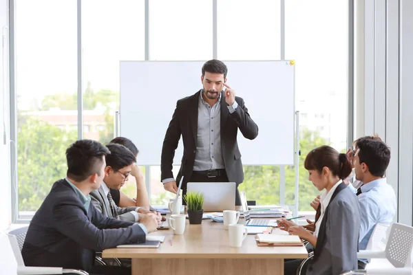 Kaukasiska föreläsare ger offentlig presentation med företagets företag diagram resultat på vit tavla i mötesrum och multietniska affärsmän uppmärksammar (utbildning eller seminarium koncept) — Stockfoto